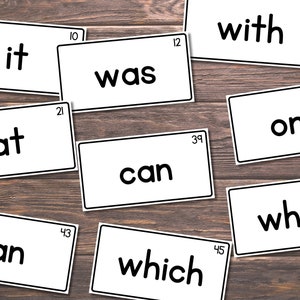 May include: A set of white cards with black text on a wooden surface. The cards contain the words "it", "was", "with", "at", "can", "one", "what", "an", "which".