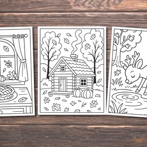 May include: Three black and white coloring pages featuring autumn themes. One shows a window with pumpkins and a pie, another a cabin with pumpkins, and the last a deer by a pond. The images are on a wooden background.