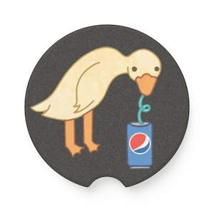May include: A round, black car coaster featuring a cartoon goose drinking from a Pepsi can with a straw. The goose is yellow with orange feet and beak. The Pepsi can is blue with the Pepsi logo.