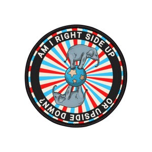 May include: Circular patch with a circus theme. The design features two gray elephants, one upright and one inverted, balancing on a blue ball with stars. The text reads "AM I RIGHT SIDE UP OR UPSIDE DOWN?" in a red, white, and blue color scheme.