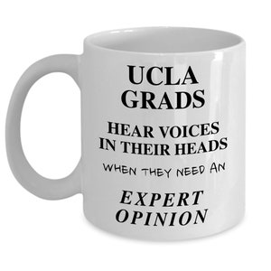 May include: White ceramic coffee mug with black text that reads "UCLA GRADS HEAR VOICES IN THEIR HEADS WHEN THEY NEED AN EXPERT OPINION".