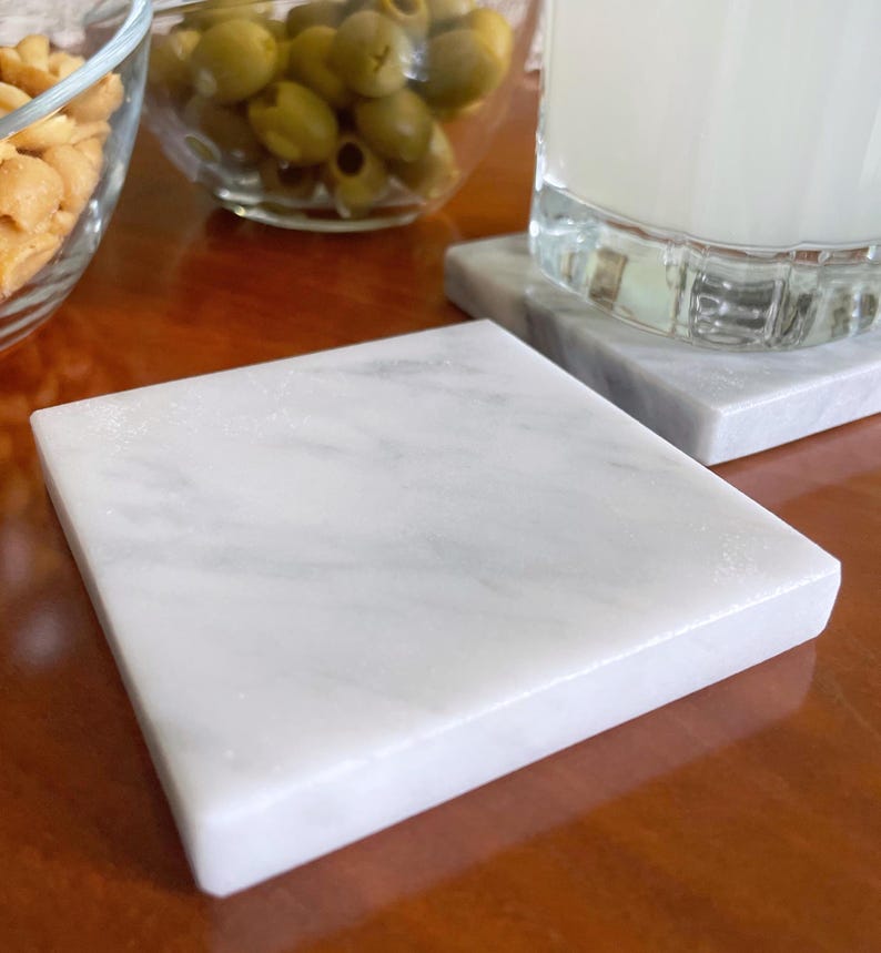 Sottobicchiere in marmo bianco Carrara dal design minimalista e raffinato. Superficie leggermente ruvida e angoli smussati. La forma quadrata e le dimensioni compatte li rendono perfetti per qualsiasi tipo di bicchiere, sia da vino che da cocktail.