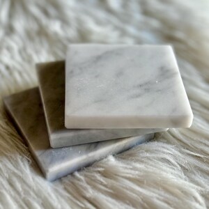 Sottobicchiere in marmo bianco Carrara dal design minimalista e raffinato. Superficie leggermente ruvida e angoli smussati. La forma quadrata e le dimensioni compatte li rendono perfetti per qualsiasi tipo di bicchiere, sia da vino che da cocktail.