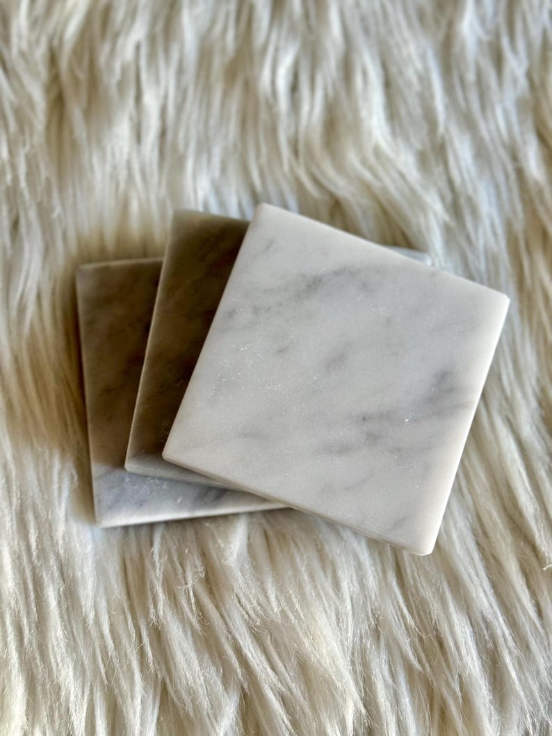 Sottobicchiere in marmo bianco Carrara dal design minimalista e raffinato. Superficie leggermente ruvida e angoli smussati. La forma quadrata e le dimensioni compatte li rendono perfetti per qualsiasi tipo di bicchiere, sia da vino che da cocktail.