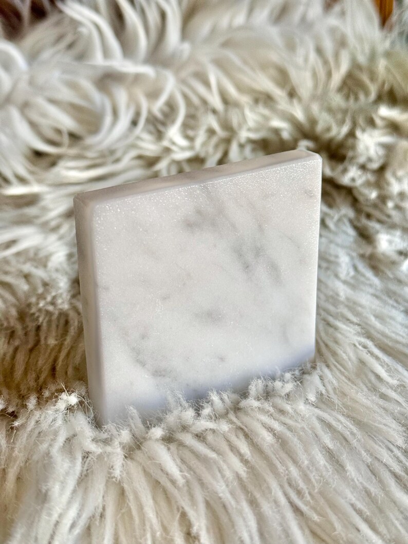 Sottobicchiere in marmo bianco Carrara dal design minimalista e raffinato. Superficie leggermente ruvida e angoli smussati. La forma quadrata e le dimensioni compatte li rendono perfetti per qualsiasi tipo di bicchiere, sia da vino che da cocktail.
