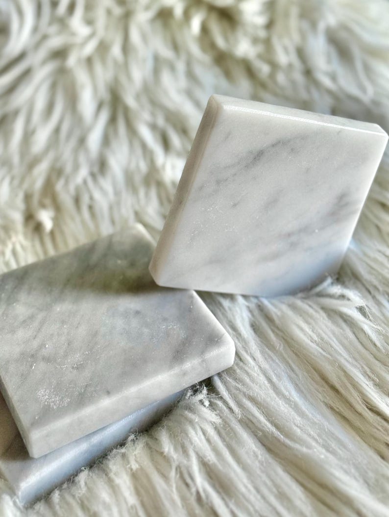 Sottobicchiere in marmo bianco Carrara dal design minimalista e raffinato. Superficie leggermente ruvida e angoli smussati. La forma quadrata e le dimensioni compatte li rendono perfetti per qualsiasi tipo di bicchiere, sia da vino che da cocktail.
