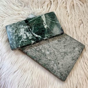 Vassoi in marmo Verde Guatemala dal colore verde intenso e costellati da vene bianche. Forma rettangolare, angoli totalmente smussati. Uno è lucido e l'altro è leggermente ruvido. Possono essere usati come portacandele o per accogliere vari oggetti.