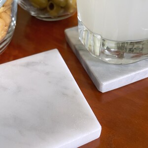 Sottobicchieri in marmo bianco Carrara dal design minimalista e raffinato. Superficie leggermente ruvida e angoli smussati. La forma quadrata e le dimensioni compatte li rendono perfetti per qualsiasi tipo di bicchiere, sia da vino che da cocktail.