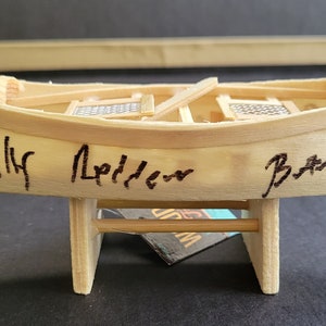 May include: A wooden canoe model signed by Billy Idol and Brad Paisley. The canoe is on a wooden stand and has a small silver tag with the number AB11206.