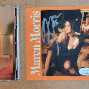 May include: A CD case with a woman holding a cocktail with a lemon slice. Beside it is an orange card with "Maren Morris" and an autograph. A JSA authentication certificate is on the right.