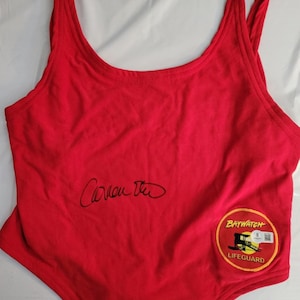 May include: A red Baywatch lifeguard swimsuit with a scoop neck and thin straps. The swimsuit has a Baywatch Lifeguard patch and a signature. The swimsuit is a size small.