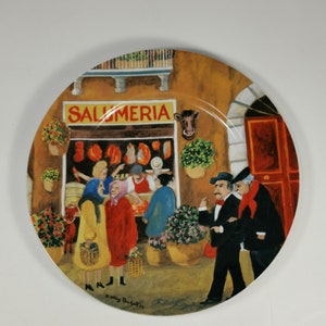 May include: A colourful ceramic plate with a painted scene of a street in Italy. The plate features a shop called "Salumeria" with people shopping and a red door in the background.
