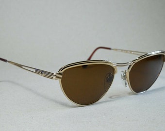 May include: Gold-tone aviator sunglasses with brown lenses. The sunglasses have a double-bridge design and a thin metal frame.