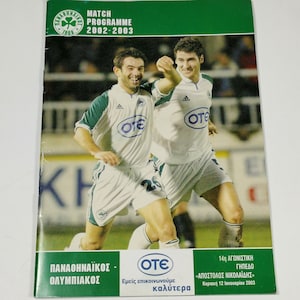 Può includere: Una copertina di programma di partita verde e bianca con due calciatori in azione. La copertina include il testo "MATCH PROGRAMME 2002-2003" e i loghi delle squadre. La parte inferiore della copertina presenta testo greco e la data "Κυριακή 12 Ιανουαρίου 2003."