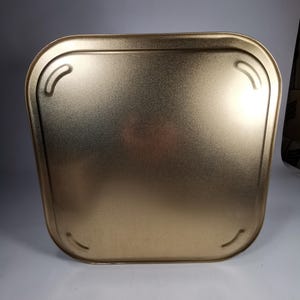 Op de afbeelding: Een gouden metalen dienblad met afgeronde randen en een glad oppervlak. Het dienblad heeft twee kleine inkepingen aan elke kant.