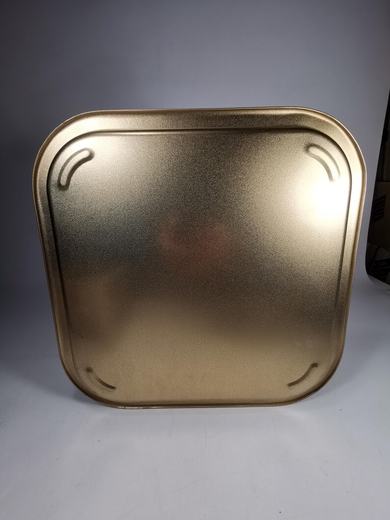 Op de afbeelding: Een gouden metalen dienblad met afgeronde randen en een glad oppervlak. Het dienblad heeft twee kleine inkepingen aan elke kant.