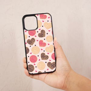 May include: A black phone case with a white background and a pattern of pink and brown heart-shaped pastries.