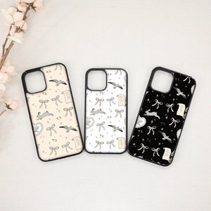 May include: Three phone cases with black borders, each featuring a different background color and pattern. The patterns include rabbits, bows, hearts, scrolls, and seagulls. The text "T.S." is repeated throughout the designs.
