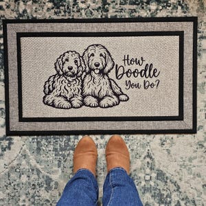 May include: A gray doormat with black trim features a black and white illustration of two doodle dogs and the text "How Doodle You Do?"