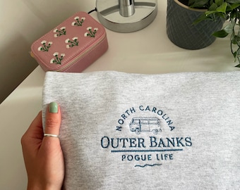 Puede incluir: Sudadera gris con el texto bordado "NORTH CAROLINA OUTER BANKS POGUE LIFE" y un gráfico de furgoneta vintage.