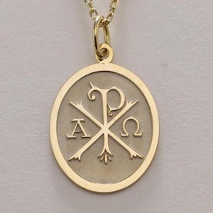Può includere: Una collana con pendente dorato con un pendente circolare raffigurante un simbolo religioso. Il pendente ha una catena e una chiusura. Il simbolo include le lettere Alfa, Chi e Omega, con frecce che si incrociano.