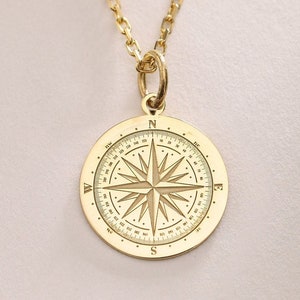 Op de afbeelding: Een gouden kompas hanger ketting met een gedetailleerd kompas ontwerp en een ketting.