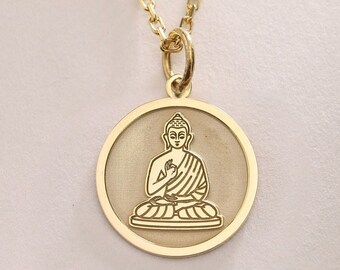 May include: Gold necklace with a round pendant featuring a detailed outline of a seated Buddha.
