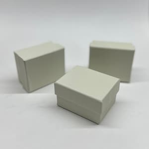 Op de afbeelding: Drie kleine, witte kartonnen dozen. De dozen zijn rechthoekig en hebben een gladde, matte afwerking.