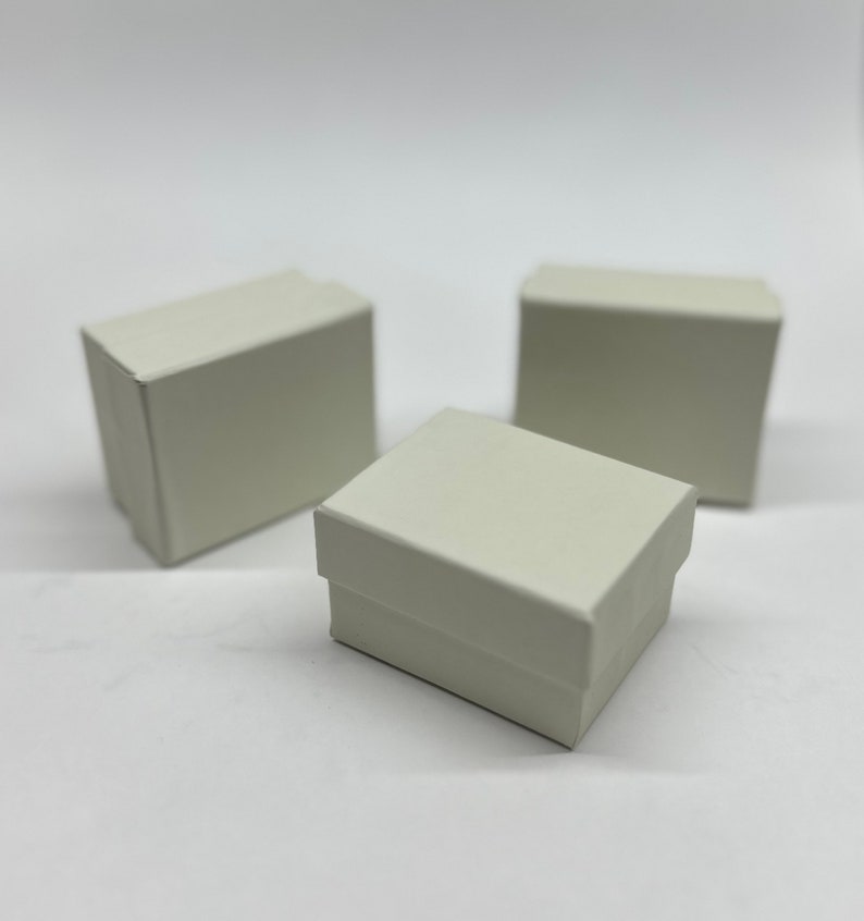 Op de afbeelding: Drie kleine, witte kartonnen dozen. De dozen zijn rechthoekig en hebben een gladde, matte afwerking.