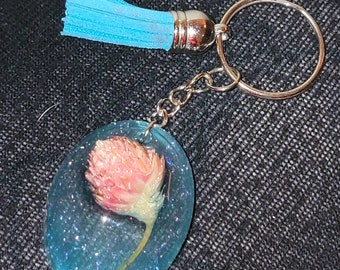 Llavero de resina de purpurina azul hecho a mano con flor rosa