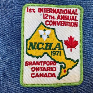 May include: A white patch with green edging, featuring a yellow outline of Canada with the text "1st International 12th Annual Convention NCHA 1971 Brantford Ontario Canada" and a red maple leaf.