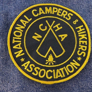 May include: A yellow and black embroidered patch with the text "National Campers & Hikers Association" and a crossed tent design with a campfire in the center.