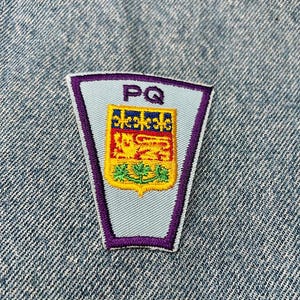 May include: Purple and white embroidered patch with a crest featuring a lion and a floral design. The patch has the letters "PQ" in the top center.