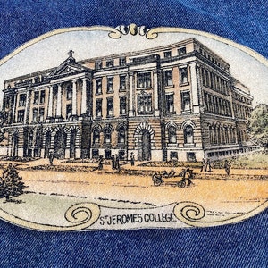 May include: A vintage-style oval patch with a detailed illustration of a large brick building. The building has many windows and a central entrance. The patch is beige with brown and black details. The text "ST. JEROMES COLLEGE" is printed at the bottom of the patch.