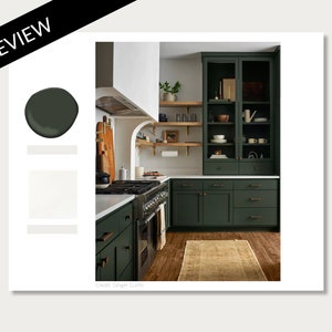 May include: A kitchen with dark green cabinets, a white countertop, and a brown wood floor. The cabinets have brass hardware and glass doors. There is a large range with a black hood above it. The kitchen has a modern farmhouse style.