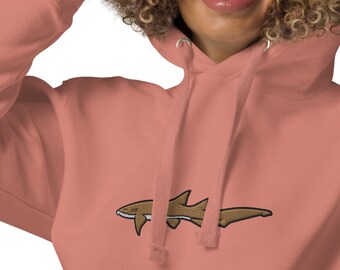 Pode incluir: Um moletom rosa coral com um design de tubarão bordado marrom na frente.