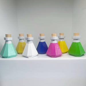 May include: Seven colorful potion bottles with geometric shapes. Each bottle has a different color liquid inside, including green, yellow, white, blue, pink, and teal. The bottles have a wooden cork and a white neck.