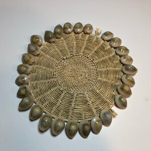 May include: A round woven coaster with a decorative border of white and brown seashells.