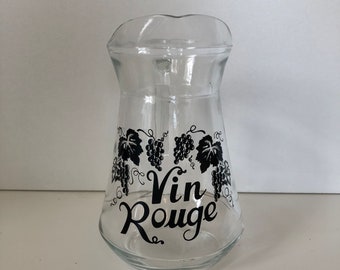 Puede incluir: Una jarra de vidrio transparente con un diseño en blanco y negro de uvas y el texto "Vin Rouge".