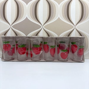 May include: A pack of six clear drinking glasses, each featuring a red apple design with green leaves. The glasses are packaged in a cardboard container and wrapped in plastic. The apple design is repeated on each glass.