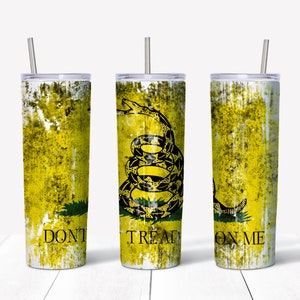 Può includere: Tre bicchieri isolati in acciaio inossidabile con coperchi e cannucce. Ogni bicchiere presenta un design giallo e invecchiato con un serpente nero arrotolato e le parole "DON'T TREAD ON ME".