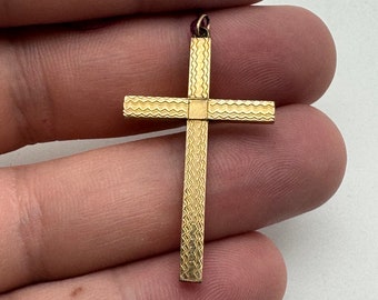 May include: A gold cross pendant with a textured surface. The cross is approximately 5 cm long.