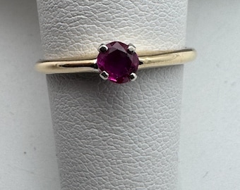 May include: A gold ring with a single round ruby gemstone.