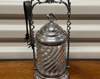 May include: Silver plated glass jar with a twisted glass design and a silver plated lid and tongs. The jar is on a silver plated stand with a decorative design.