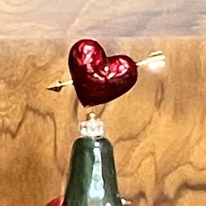 May include: A green ceramic Christmas tree with red lips and colorful ornaments. A red heart with an arrow is on top of the tree.