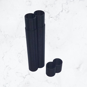 Puede incluir: Cortadores de galletas negros de varias formas. El conjunto incluye dos cilindros altos y un cortador en forma de ocho. Los cortadores son de un material oscuro y están sobre un fondo blanco marmolado.