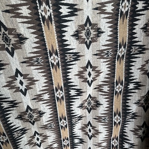 May include: A close-up of a fabric with a geometric pattern in shades of brown, beige, and white. The pattern features repeating diamond shapes and zig-zag lines.
