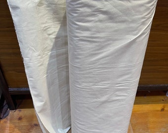 May include: A roll of white fabric, folded and rolled up. The fabric is smooth and appears to be cotton.