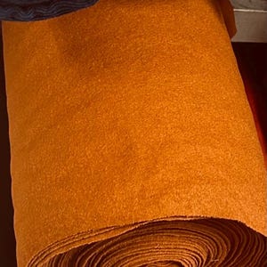 May include: A roll of orange felt fabric. The fabric is soft and fuzzy, and it is perfect for crafting projects.