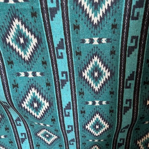 May include: Teal, black and white woven fabric with a geometric pattern. The pattern features diamonds, zigzags and other abstract shapes.